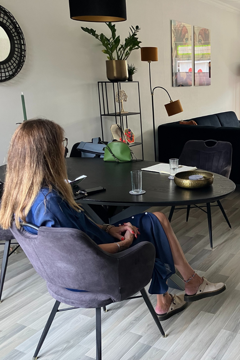 Ellen zit ontspannen aan tafel in haar geïsoleerde jaren ’30 woning, klaar voor een comfortabeler huis en lagere energiekosten.